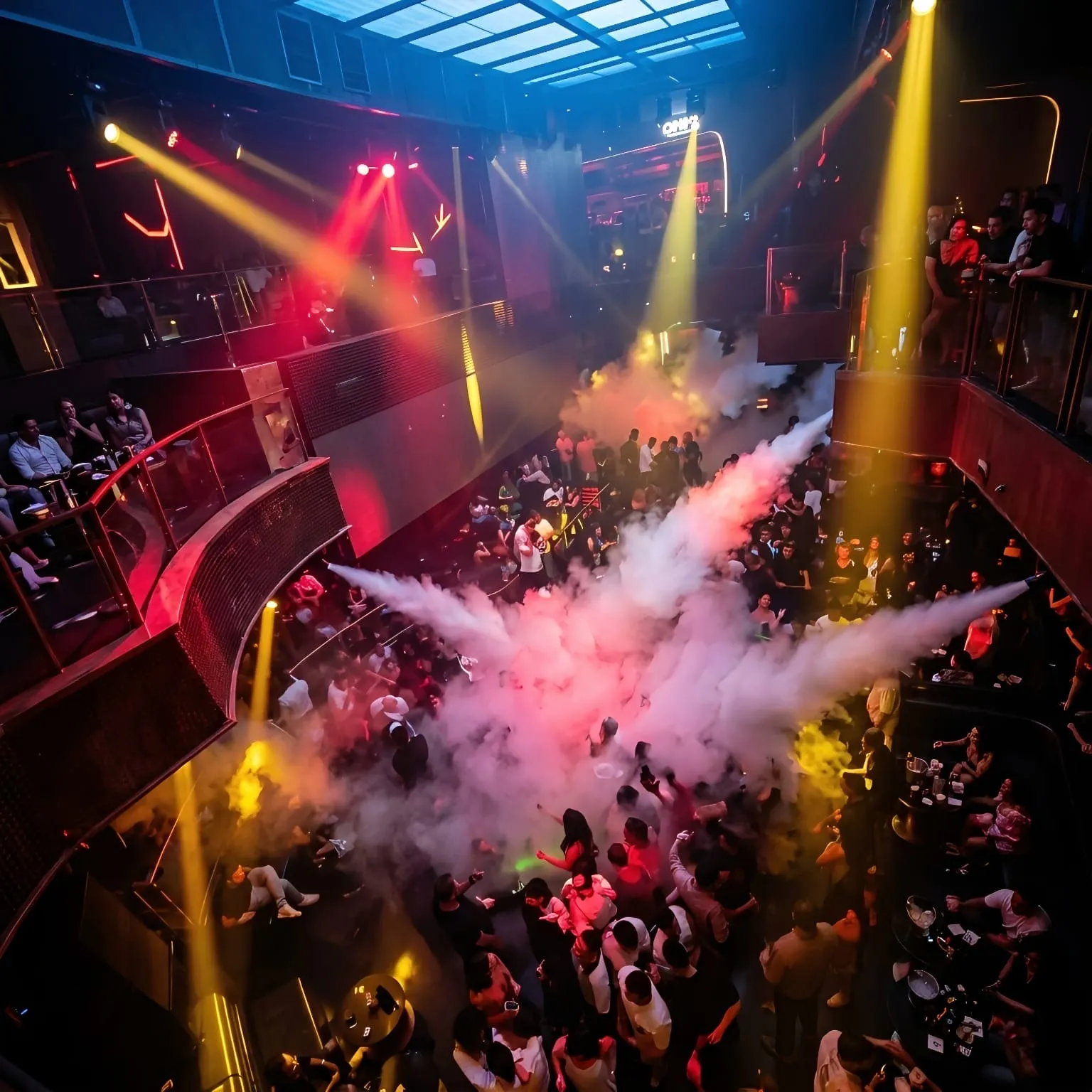 CO2 jets blasting white fog over a packed floor, seen from the balconies above
